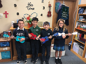 Four students pose with ukeleles in a classroom
