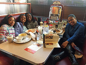 Happy students with an adult sitting a diner table