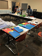 Folder supplies on table with volunteers working