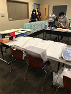 School materials on table with volunteers working