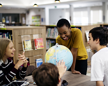 High school students talking around a globe of the earth in a classroom