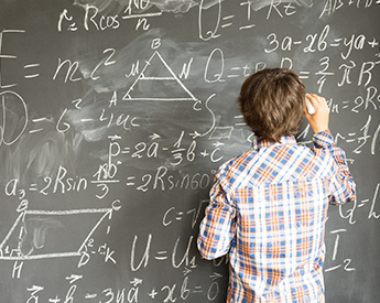 high school student working through a math problem on the chalkboard