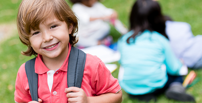 Happy preschool boy with backpack ready for school