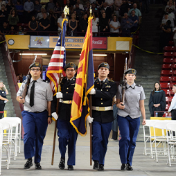 Students in uniform carrying USA flag and Arizona flag